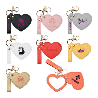 Heart-Shaped Compact Mirror with Keychain - A heart-shaped compact mirror with a keychain, featuring various coloured designs and logos in pink, black, white, red, and yellow.