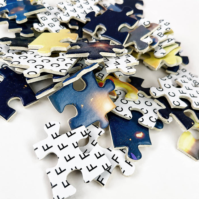 Custom Gift Box Jigsaw Puzzle - A pile of jigsaw puzzle pieces featuring a cosmic design in blue, yellow, and black hues, with some pieces showing a grid pattern.