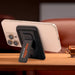 Wally Stand - A phone stand featuring a black case with a logo, securely holding a smartphone in an upright position.