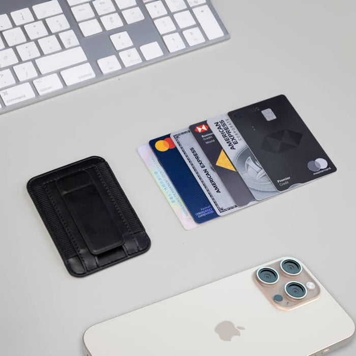 Wally Stand - A black card holder with multiple credit cards beside a smartphone and a white keyboard on a light surface.