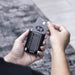 Wally Stand - A black wallet with a card in hand, featuring a sleek design and metal accents.