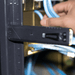Rechargeable Work Light - A black tool with a handle and measurement markings, positioned near blue cables in a rack.
