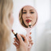 Chic Princess-Style Handheld Makeup Mirror - A pink handheld makeup mirror reflects a person applying lipstick, with a soft, neutral background.