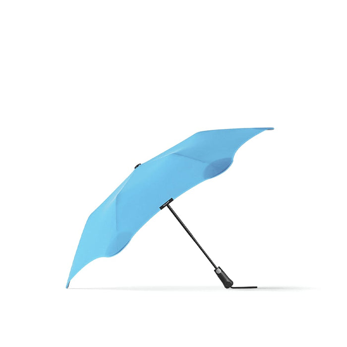 BLUNT Metro Umbrella - A light blue BLUNT Metro umbrella with a sturdy black handle and a unique design for enhanced stability.