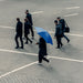 BLUNT Exec Umbrella - A group of people walking on a pavement, with one person holding a blue umbrella.