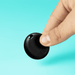SeekTag Factory Direct - A circular black tracking device held between fingers, set against a bright turquoise background.