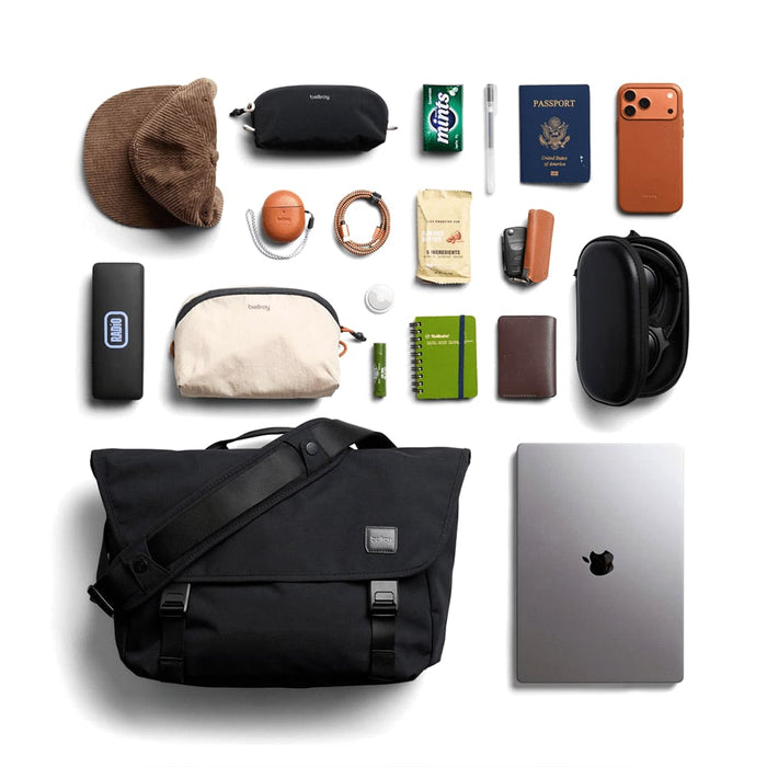 Bellroy Classic Messenger 13L - A black messenger bag with various items including sunglasses, a hat, a laptop, and a wallet, arranged on a flat surface.