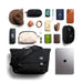 Bellroy Classic Messenger 13L - A black messenger bag with various items including sunglasses, a hat, a laptop, and a wallet, arranged on a flat surface.