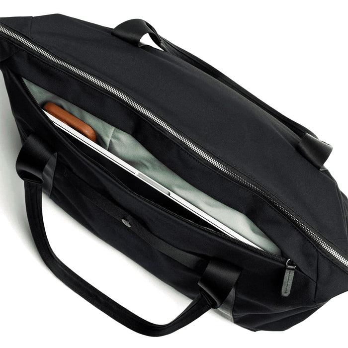 Bellroy Classic Tote - A black tote bag with an open zipper, revealing a light grey interior and a laptop inside. It features two handles and a logo.