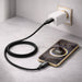 100W Magnetic Round Braided Charging Cable - A black braided charging cable connected to a phone and a wall charger. The phone displays a battery charge percentage.