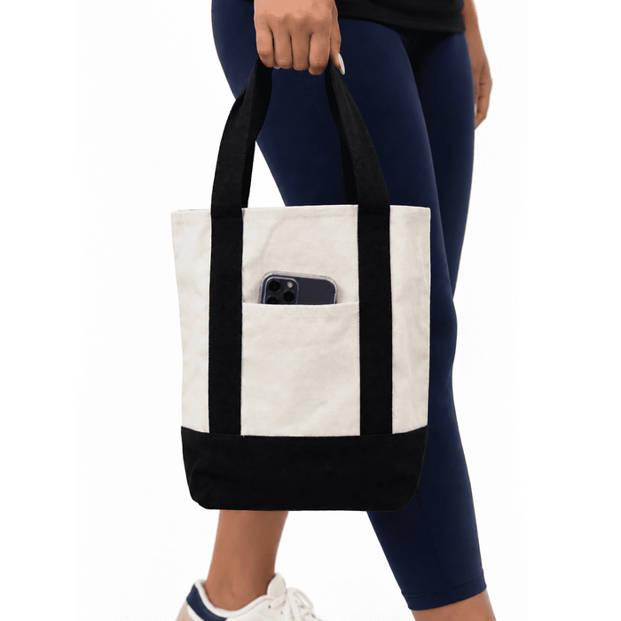 Mini Canvas Tote - A mini canvas tote in cream with a black bottom and straps, featuring an exterior pocket.