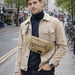 Canvas Waist Bag - A man wearing a tan canvas waist bag over a black turtleneck, standing on a city street.