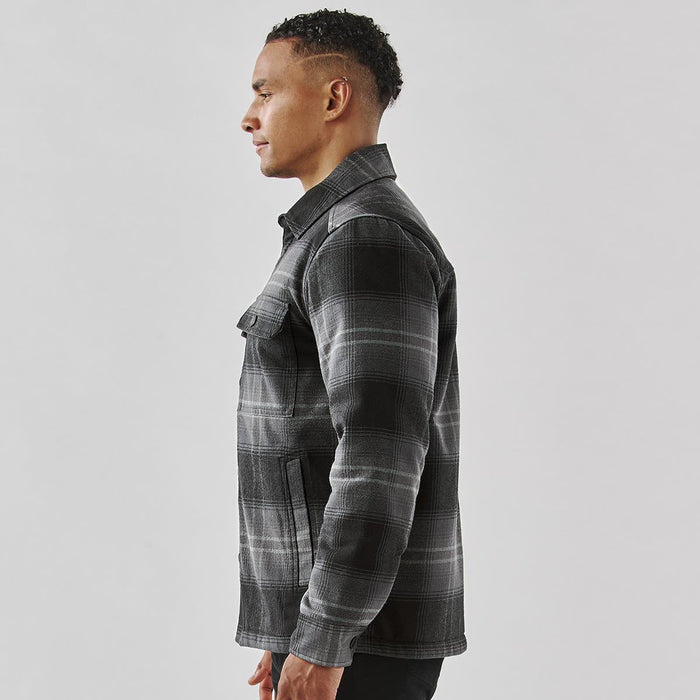 Men's Highland Sherpa Lined Plaid Jacket - A men's plaid jacket in black and grey, featuring a Sherpa lining and a side view of the wearer. It has a logo.