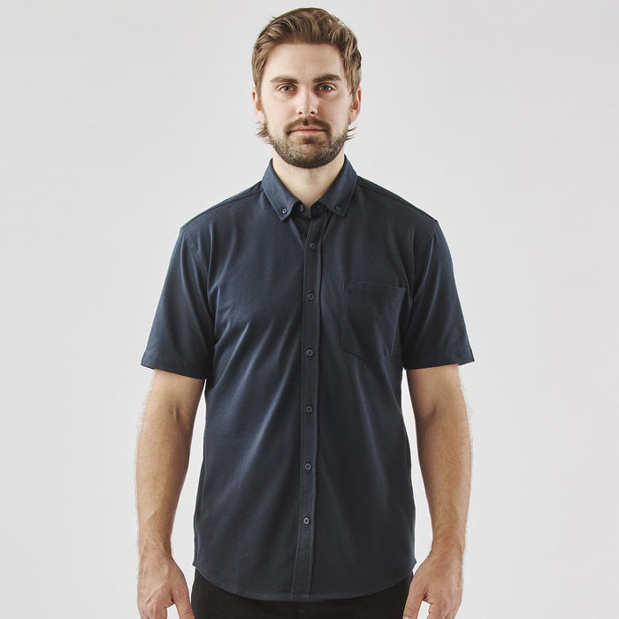 Men's Sonora Short Sleeve Knit Shirt - A man wearing a navy blue short sleeve button-up shirt with a pocket and a logo on the chest.
