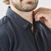 Men's Sonora Short Sleeve Knit Shirt - A close-up of a man's neck and collar in a dark navy short sleeve button-up shirt, featuring a logo.