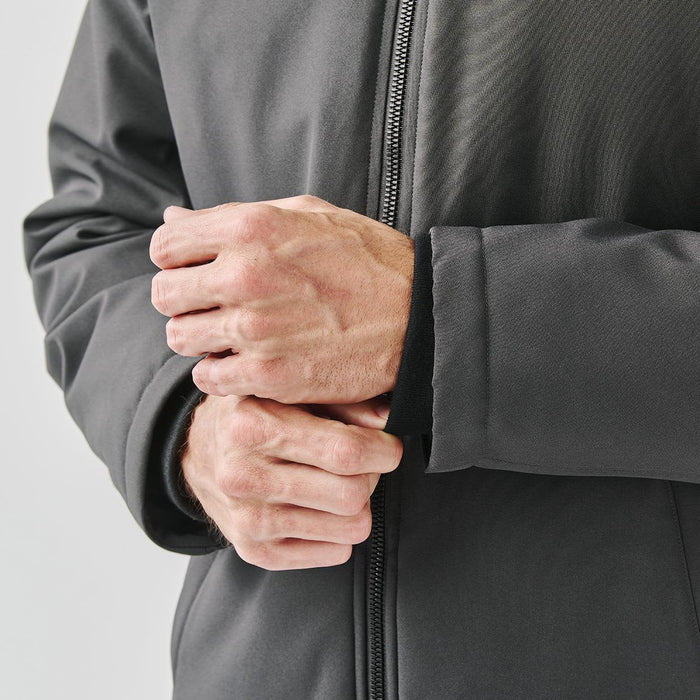 Men's Athabasca Thermal Jacket - A close-up of a person's hands adjusting the cuffs of a dark grey thermal jacket with a logo.