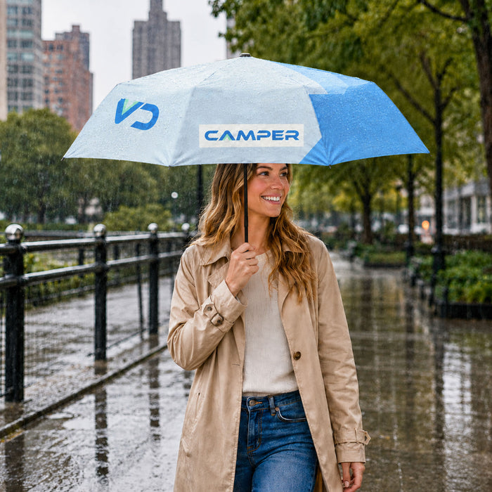Anti-rebound Folding Umbrella - A light blue and white folding umbrella held by a woman wearing a beige trench coat, standing in the rain.