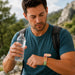 Medicine Box Wristband - A man in a blue shirt holds a water bottle while looking at a green and pink Medicine Box Wristband on his wrist.