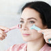Ice Massager Roller Double Head - A woman using a double-headed ice massager roller in pink and blue, applying it to her face.