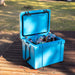 25L Cooler Box - A blue 25L cooler box is filled with various soft drink bottles and water bottles, sitting on a wooden surface.