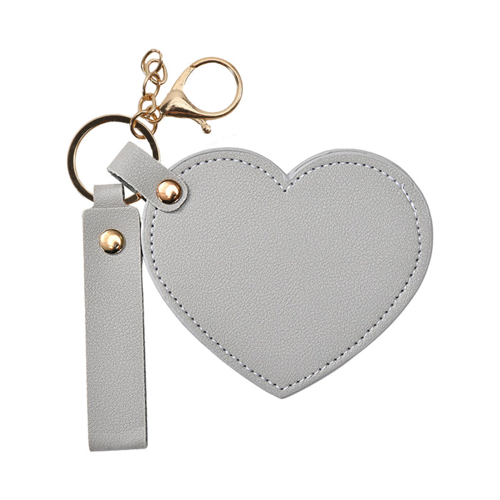 Heart-Shaped Compact Mirror with Keychain - A heart-shaped compact mirror in grey with a keychain attachment and a gold clasp.