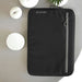 Work Essentials Pack - A black laptop sleeve featuring a front zipper pocket and a logo. Set against a neutral background with candles.