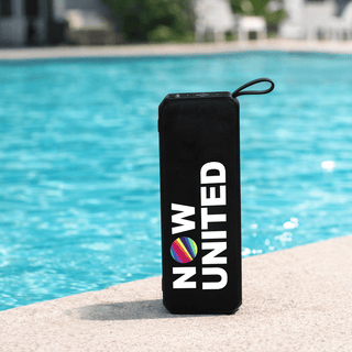 Sunrise Solar Speaker - A black portable speaker with a round logo, sitting by a blue pool.