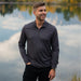 Men's Monterey 1/4 Zip Pullover - A men's charcoal grey 1/4 zip pullover in a scenic outdoor setting by a body of water.