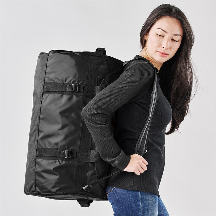 Stormtech Gear Bag Medium - A medium black duffle bag featured being carried by a person, with adjustable straps and buckles visible.