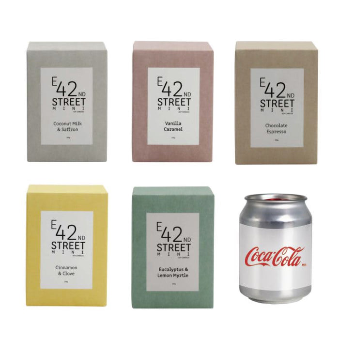Mini East 42nd Street Can Candle - A set of six square candle boxes in various pastel colours: coconut milk and saffron, vanilla caramel, chocolate espresso, cinnamon and clove, eucalyptus and lemon myrtle. A Coca-Cola can is beside them.
