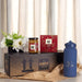 Festive Essentials Set - A blue drink bottle, a jar of jam, a box of biscuits, and a vase of flowers arranged on a decorative box.