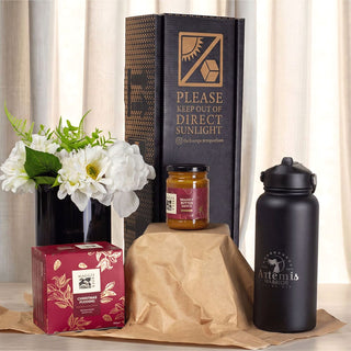 Festive Essentials Set - A festive essentials set featuring a black drink bottle, a candle jar, a gift box, and a flower arrangement.
