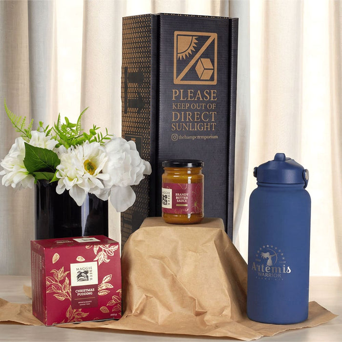 Festive Essentials Set - A blue drink bottle, a jar, a box, and a vase with flowers arranged on brown packaging.