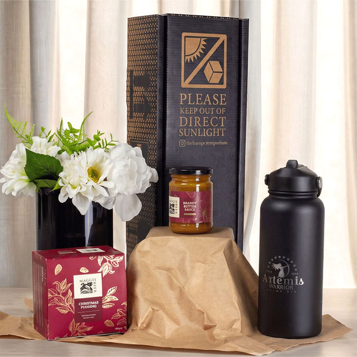 Festive Essentials Set - A festive essentials set featuring a black drink bottle, a candle jar, a gift box, and a flower arrangement.