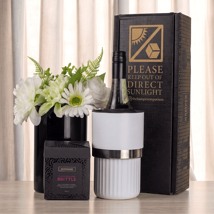 The Entertainer Set - A wine bottle in a white cooler, surrounded by a black box and a flower arrangement in a black vase.
