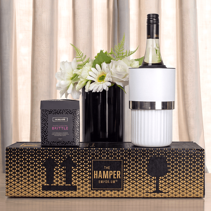 The Entertainer Set - A wine bottle in a white cooler, paired with a black box of brittle, set on a decorative box with a logo.