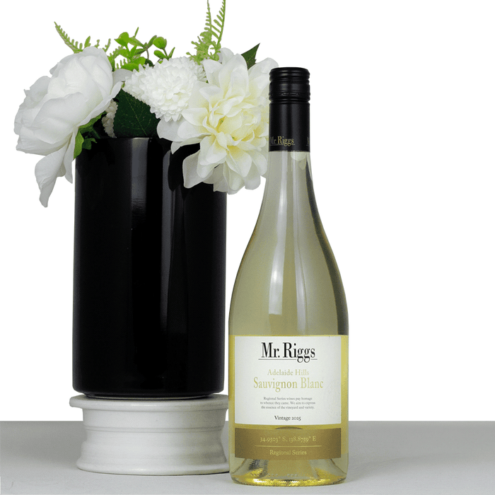 The Entertainer Set - A bottle of white Sauvignon Blanc wine beside a black vase with white flowers. The bottle has a label and branding.