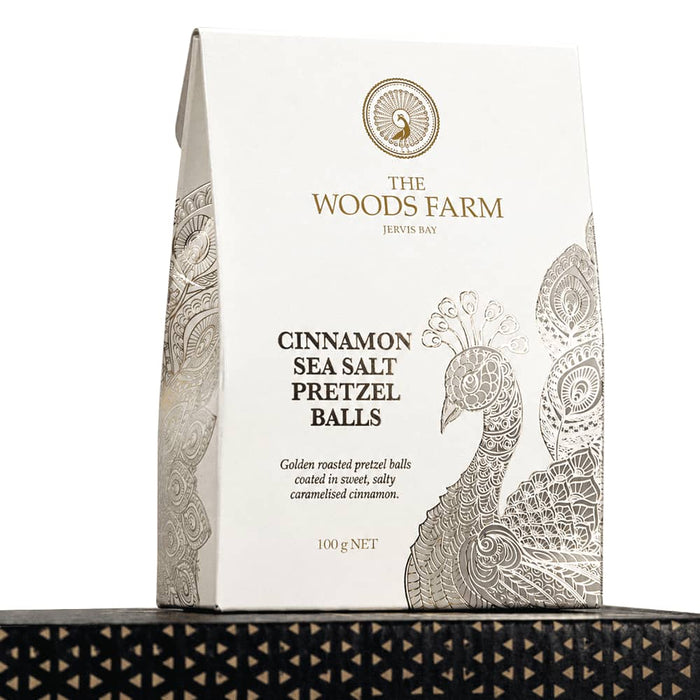 The Blunt Umbrella All Weather Set - A bag of 100g cinnamon sea salt pretzel balls in a white and gold design, featuring a peacock motif.