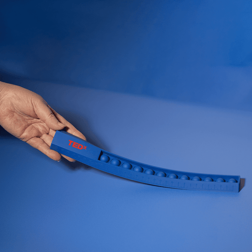 30cm Popper Ruler - A blue 30cm popper ruler with a hand holding it, featuring a textured popping surface and a logo.