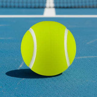 High Bounce Tennis Ball - A bright yellow tennis ball sits on a blue court, featuring white stripes and a smooth texture.