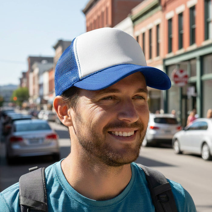 White Front 5 Panel Trucker Mesh Cap - A white and blue 5-panel trucker mesh cap worn by a man in a city setting with cars in the background.