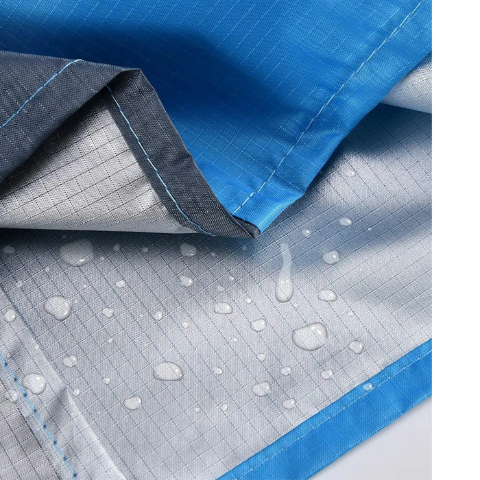 Polyester Picnic Blanket in Pouch - A close-up of a blue polyester picnic blanket featuring a water-resistant underside with droplets. It has a logo.