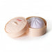 Squishy Bun - A squishy bun in a round, light peach container with a lid, featuring a soft purple bun inside.