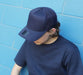 Cotton/Mesh - A navy blue cap with a mesh back, resting on the head of a person wearing a matching navy shirt.