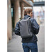 Hedmark Commuter Backpack - A person wearing a black jacket carries a grey Hedmark Commuter Backpack on their back in an outdoor setting.