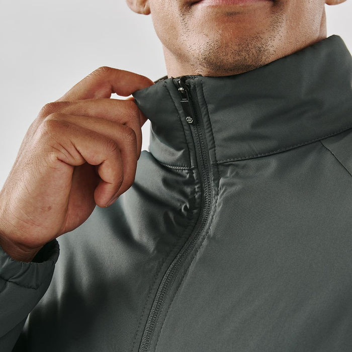 Men's Pacifica Thermal Jacket - A close-up of a man's hand adjusting the collar of a dark green thermal jacket, featuring a zipper and a logo.