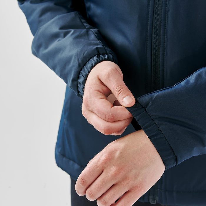 Women's Pacifica Thermal Jacket - A navy thermal jacket featuring elastic cuffs, with a person's hand adjusting the sleeve. The jacket has a logo.