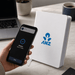 NFC A5 Smart Notebook - A white NFC A5 Smart Notebook next to a smartphone displaying a notification, with a laptop in the background.