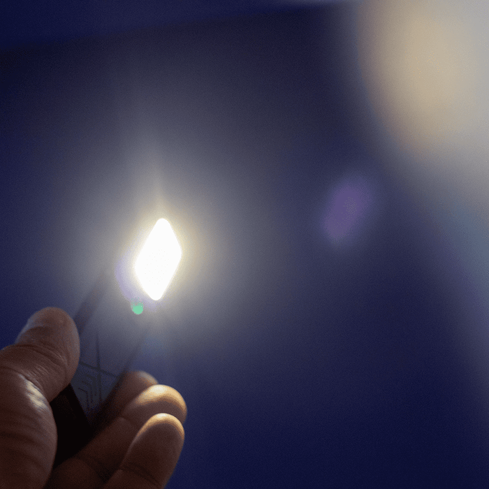 Rechargeable Work Light - A handheld rechargeable work light emits a bright white light against a blue background. It features a logo on its surface.