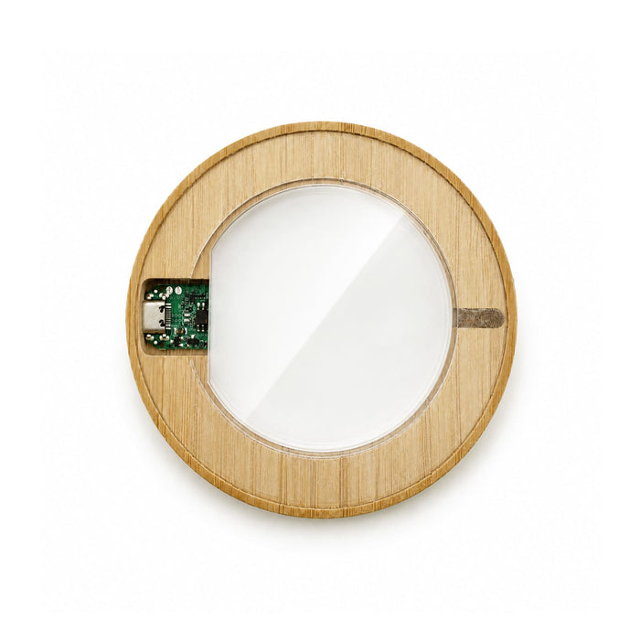 Crescent Illuminating Wireless Charger - A circular wireless charger with a bamboo outer frame and a glass centre, featuring internal electronic components.